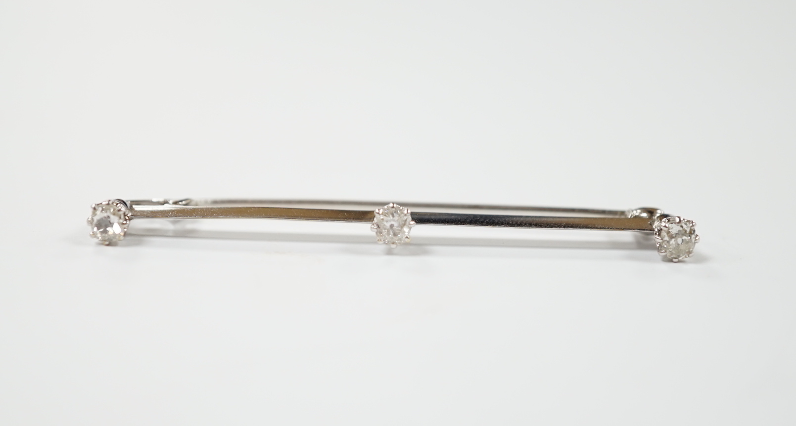 A white metal and three stone diamond set bar brooch, 56mm, gross weight 3.4 grams.